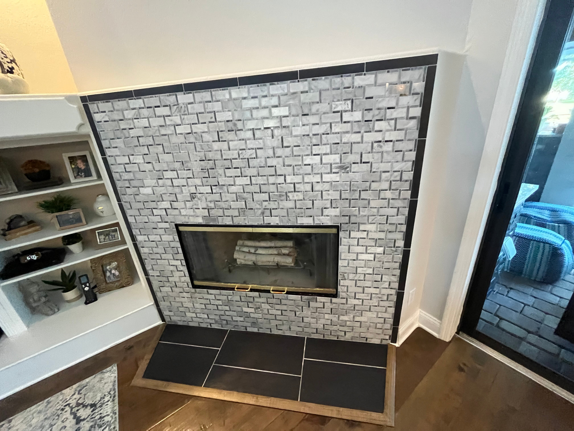 Completed fireplace with modern mosaic tile and dark border